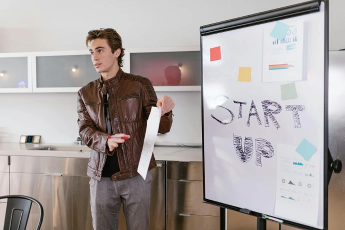 Ein junger Mann, der an einem Whiteboard steht und etwas präsentiert.